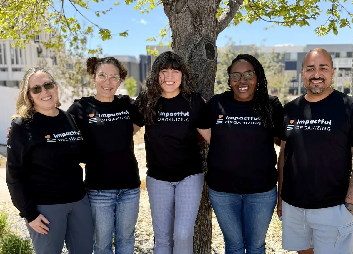 The Impactful Organizing team in matching shirts, smiling outdoors in Colorado Springs